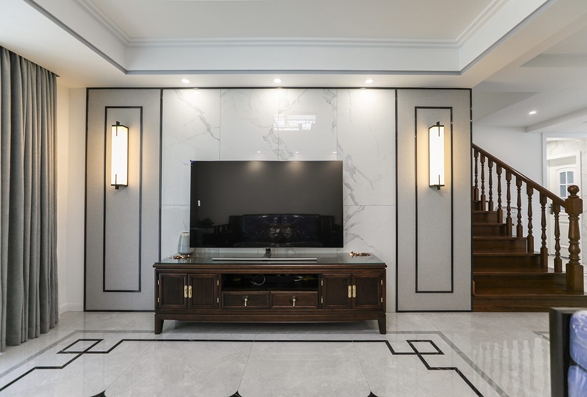 客廳是接待客人的空間、是家庭裝修的亮點所在、也是一家人活動頻率最高的區域，造型和色調必須體現時尚、簡潔、大氣為主，要讓人百看不厭，電視背景彩用防大理石瓷磚配上米色墻布，四周再用不銹鋼線條分割。造型上方形造型頂配以方形的地面瓷磚拼花。造型和色調上無不給人以簡潔、大氣、時尚的感覺。

