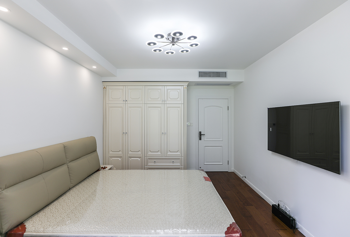 主臥布置上以實用為主，造型上以方正為主，顏色上深淺搭配地錯落有致，深色實木地板，墻頂白色乳膠漆，圓形造型吊燈，使整個空間方中帶圓，圓中有方，體現了主人端莊正派的作事風格。
