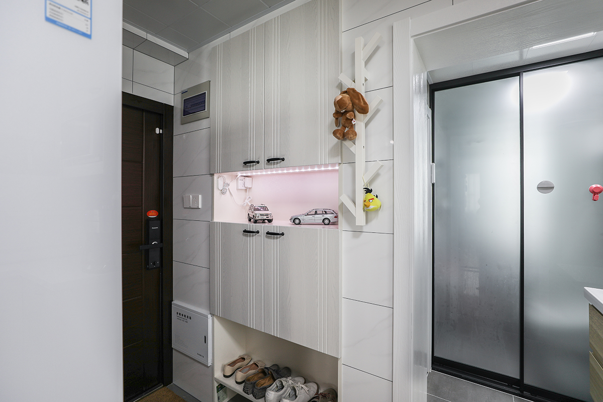 入戶玄關處采用內嵌式鞋柜，使本身局促的入戶處最大化利用，巧妙的利用燈帶增加了鞋柜層次，燈光打在擺件上讓玄關增加趣味性，同時使昏暗的角落亮起來