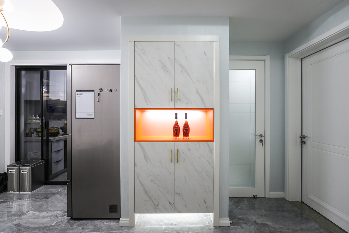 玄關采用灰色的地磚，配上仿大理石的鞋柜，配上有金屬線條的拉手，中間采用調色的鏤空色，讓真個鞋柜和客廳的背景的電大路大理石和檸檬黃調色的窗簾盒抱枕，讓整個空間更有層次感，從客廳貫穿餐廳到進門的門廳，動線和色彩都很明顯。