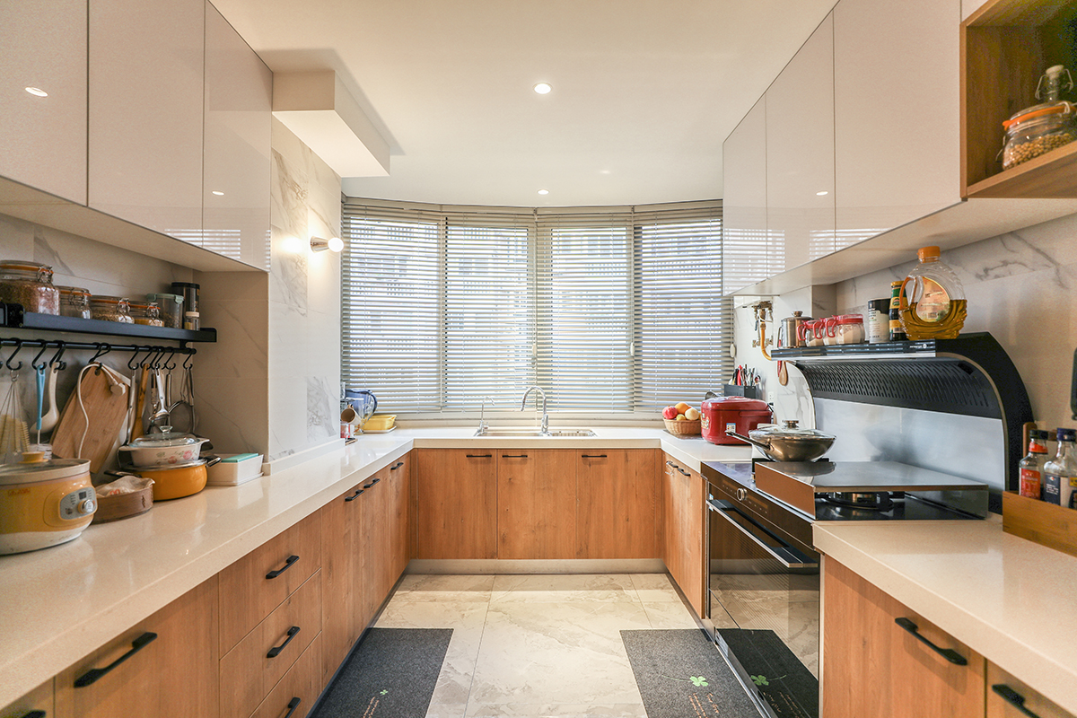 廚房采用木色色系，充分體現簡約風格，集成的煙機，白色大理石臺面和白色吊柜的合理搭配，顯現出客戶的整潔生活，木色和白色瓷磚的搭配更加的合理大氣，隨著家庭電器的不斷增加使得廚房在設計上對于電器的需求充分合理的安排。
