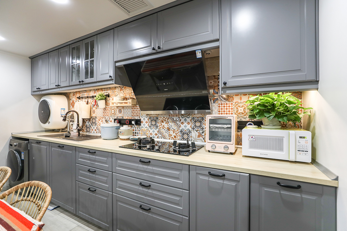 廚房區域選用模壓板櫥柜，臺面沒用選用傳統的石英石臺面或是不銹鋼臺面。而是選用了三氯氰胺樹脂板做臺面，提升了整個空間的溫度?；ùu做背景，即使臺面堆放物品再多也不會顯得空間凌亂。由于衛生間空間較小，所以櫥柜做了內嵌洗衣機柜及掛壁式洗衣機。形成一個多功能空間。
