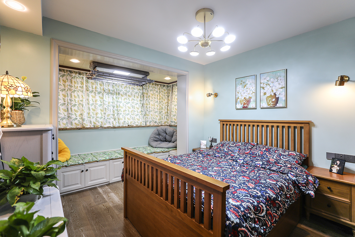 主臥背景色以淺藍色為主，選用純實木家具，陽臺做了卡座處理，會客儲物一應俱全。整體配色比較清爽。
