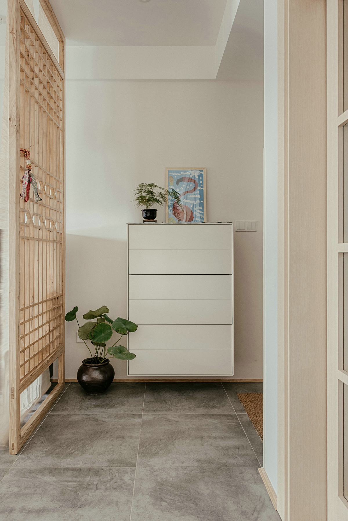 進門玄關空間略小，除了懸掛式鞋柜外，把空間分配做了隔斷，進門后并不會一眼望穿整個空間。鏤空隔斷在增強隱私性的同時又舒緩了視野，隔斷背后放置一架黑色的鋼琴，注重生活品質的業主，更喜歡平時練練鋼琴看看書，認真地思考生活的每一個細節，增添了生活的儀式感。
