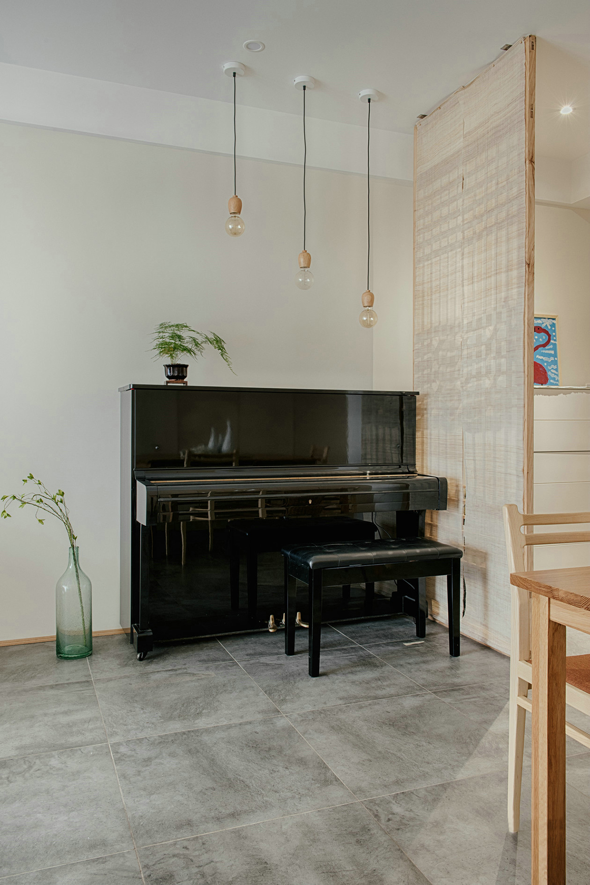 進門玄關空間略小，除了懸掛式鞋柜外，把空間分配做了隔斷，進門后并不會一眼望穿整個空間。鏤空隔斷在增強隱私性的同時又舒緩了視野，隔斷背后放置一架黑色的鋼琴，注重生活品質的業主，更喜歡平時練練鋼琴看看書，認真地思考生活的每一個細節，增添了生活的儀式感。

