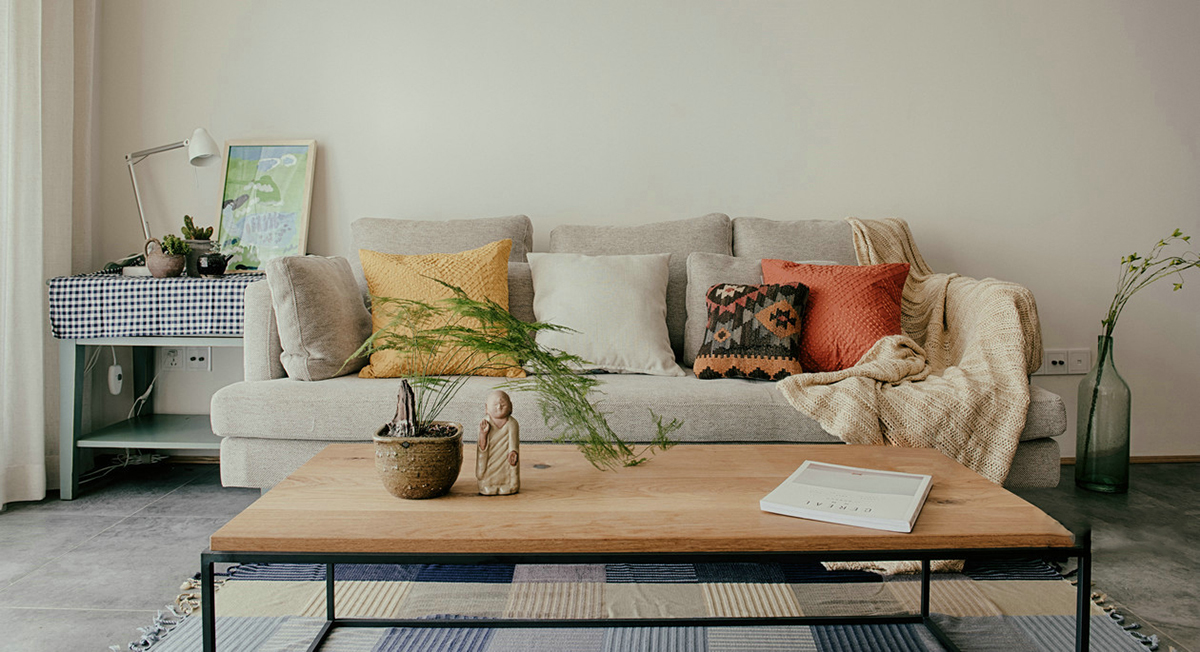 客廳空間開闊明亮。利用淺色紗幔窗簾優化自然光的吸采，讓空間擁有足夠的恬靜感。業主對日式風格很喜歡，客廳的茶幾是業主在日本旅游時帶回國?；疑牟妓嚿嘲l，沉穩大氣，搭配自然紋理的原木茶幾和座椅，讓濃郁的日式風情填滿整個空間。柔軟舒適的沙發，隨意擺放著幾個抱枕，再增加一張橙色的真皮單人椅，無形之中提升了空間的質感。
