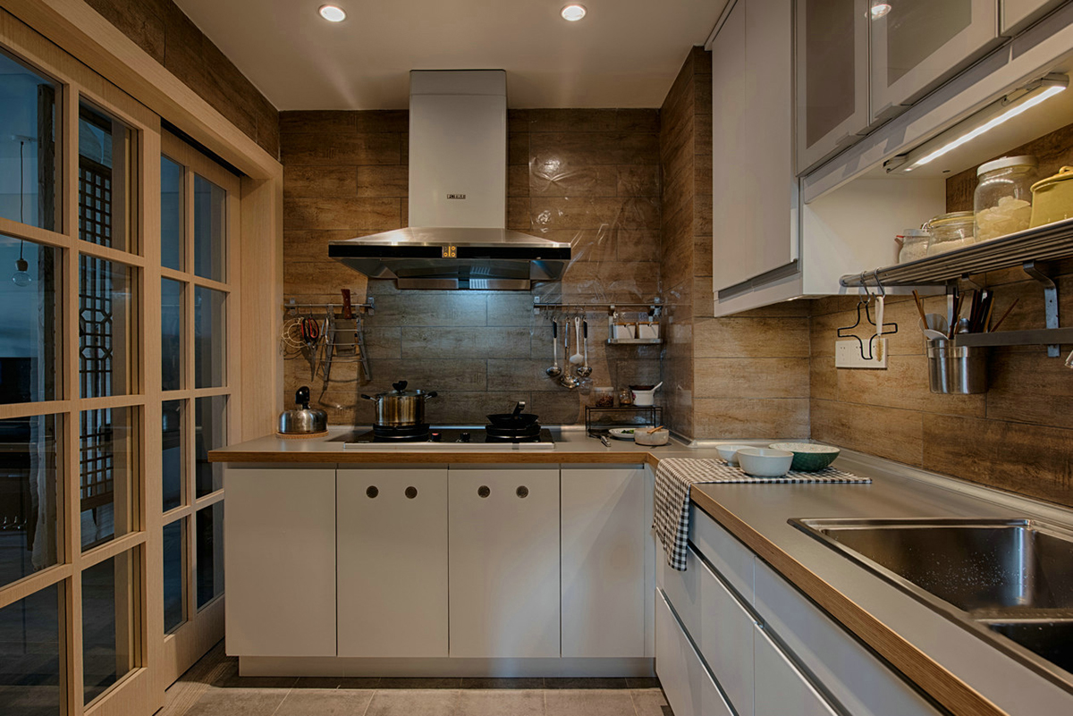 廚房清新雅致，追求整潔和舒適。不銹鋼臺面，低調不張揚，干凈明亮。深木色系墻磚，原木的韻味，讓廚房也能散發出自然氣息。業主愛旅游、愛收藏、愛養花弄草，因此在空間利用中，設計師為他們打造了一間多功能茶室，原木的小桌子，擺放著精致的茶具，讓他們在這里喝茶、看書、賞花，享受閑暇時光。
