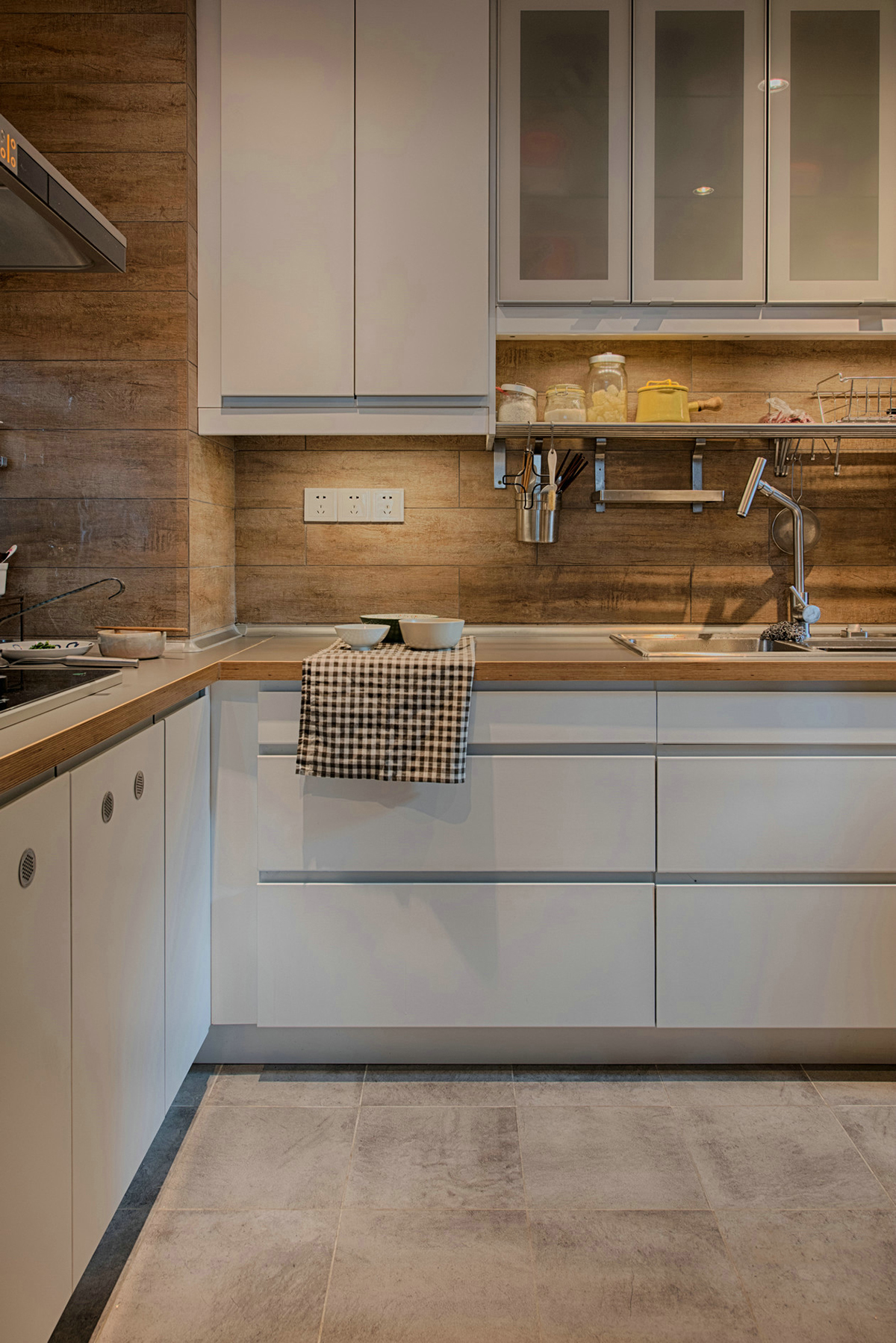 廚房清新雅致，追求整潔和舒適。不銹鋼臺面，低調不張揚，干凈明亮。深木色系墻磚，原木的韻味，讓廚房也能散發出自然氣息。業主愛旅游、愛收藏、愛養花弄草，因此在空間利用中，設計師為他們打造了一間多功能茶室，原木的小桌子，擺放著精致的茶具，讓他們在這里喝茶、看書、賞花，享受閑暇時光。
