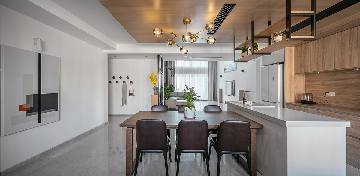 木飾面是貫穿整個(gè)空間的，顏色層次是黑白灰+木色的基調(diào)。大面積白色會(huì)使空間沒有很冷，所以用木色的溫潤(rùn)來(lái)調(diào)節(jié)整個(gè)空間溫度。讓家的感覺更溫馨。櫥柜與頂面不是一家生產(chǎn)，在施工中先確定了櫥柜顏色。帶著樣板去定制頂面顏色，整體效果基本一致。櫥柜和吧臺(tái)的位置就是原來(lái)的空中花園，打通后空間開闊，可以和客廳統(tǒng)一。為了配合整體簡(jiǎn)潔干凈的感覺，窗簾我選用木色百葉窗。透光和隱私性和布藝窗簾同等。右側(cè)的廚房是紅橡制作，為了保證實(shí)木的本質(zhì)只做了清漆。顏色質(zhì)感是市場(chǎng)銷售產(chǎn)品所達(dá)不到的。
