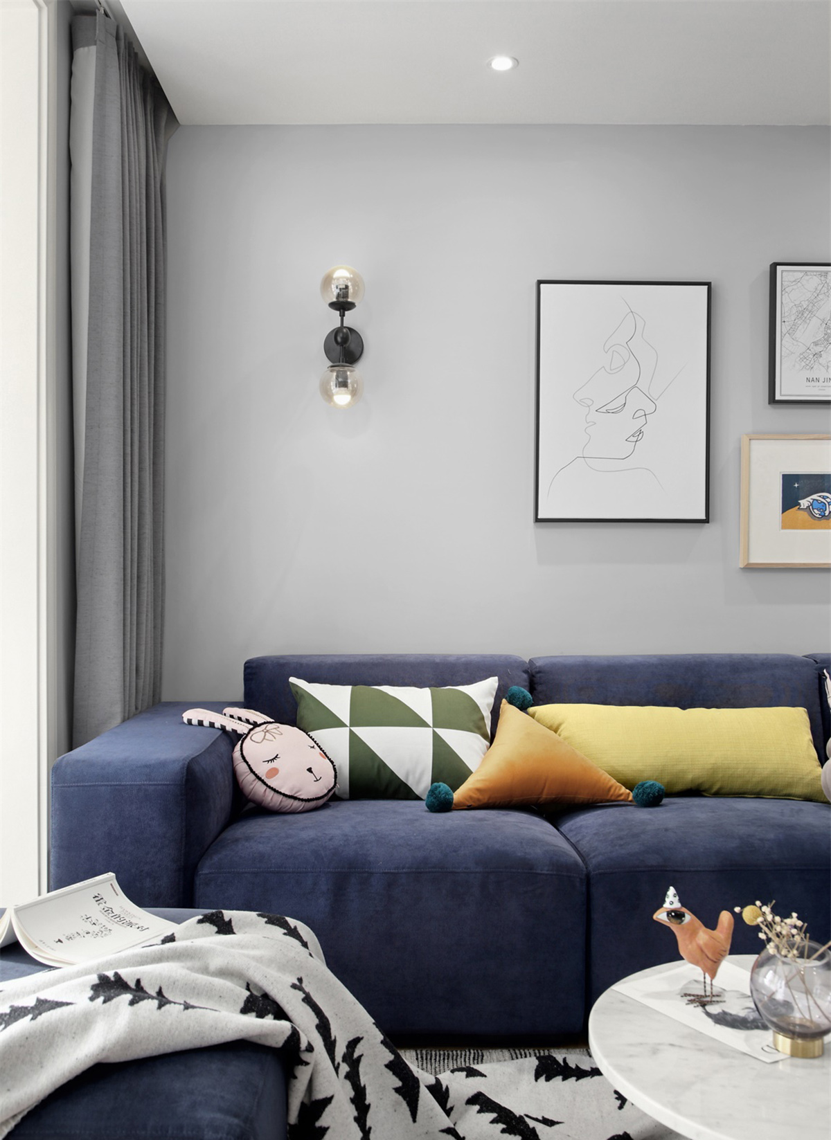 客廳以灰色墻面搭配原木色地板，簡約的背景墻設計，看起來干凈清爽，同時搭配撞色系的藍色沙發，局部亮色點綴，起到畫龍點睛的作用。
